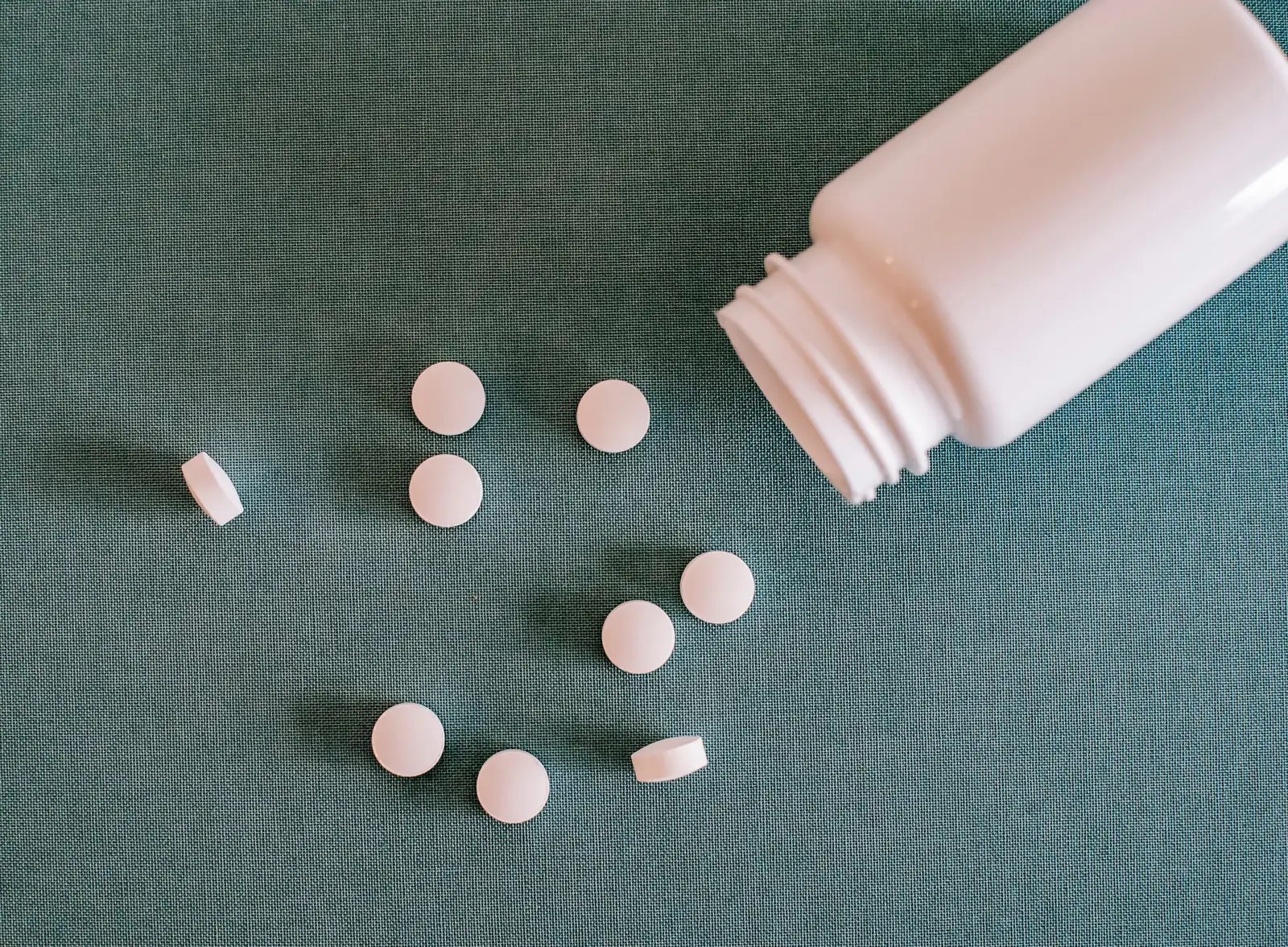Tablets beside a plain unbranded bottle